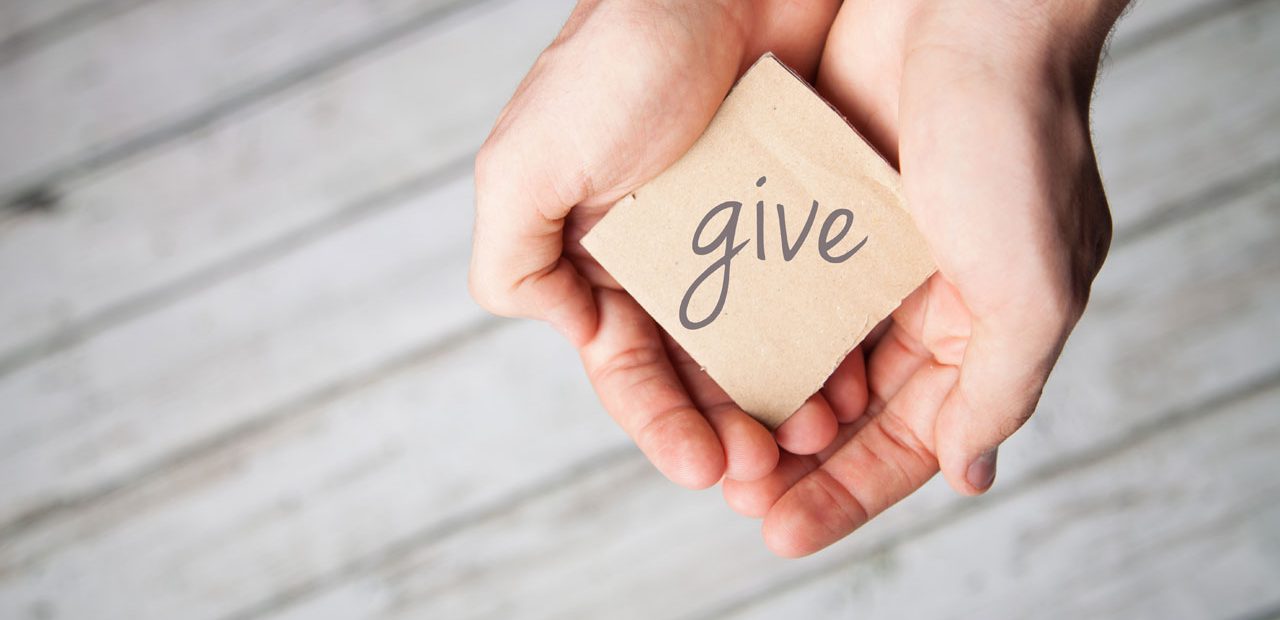 hands holding a card that says give